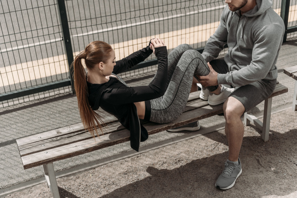 přítel drží přítelkyně nohy a pomáhá dělat sit ups - Fotografie, Obrázek