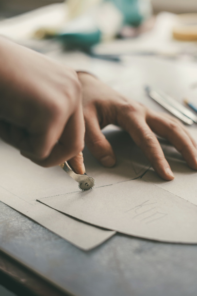 Schnappschuss eines Handwerkers, der Lederblätter nachzeichnet, um Schuhe herzustellen - Foto, Bild