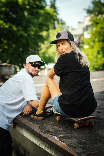 αγόρι και κορίτσι σε ένα skateboard μιλάμε με το άλλο, σε μια καλοκαιρινή μέρα - Φωτογραφία, εικόνα