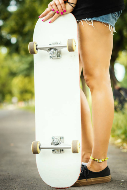menina com um skate branco fica e posa em um dia de verão
 - Foto, Imagem