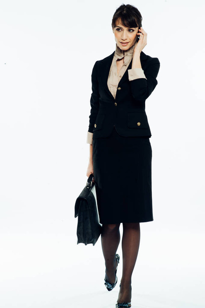 Young caucasian brunette suit dressed business woman talking with a vintage smartphone. Standing up. Studio shot. - Fotó, kép