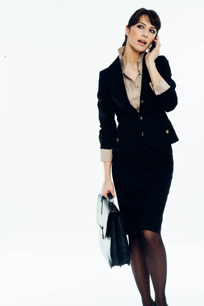 Young caucasian brunette suit dressed business woman talking with a vintage smartphone. Standing up. Studio shot. - Foto, Imagem