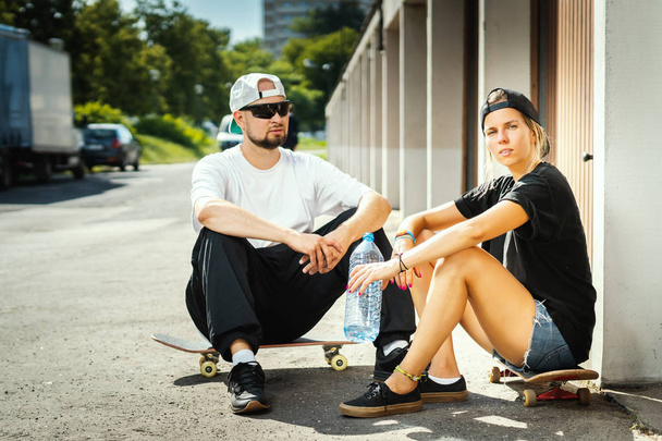 jongen en meisje met skateboards poseren op straat op een zomerdag - Foto, afbeelding