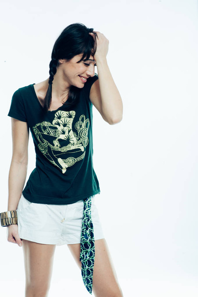 junge kaukasische Brünette mit Schweifhaaren, die ihren Spaß im Studio hat. weißer Hintergrund, grünes Hemd angezogen. Kopierraum - Foto, Bild
