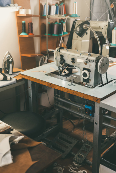 local de trabalho da costureira na loja sob medida com máquina de costura industrial elétrica
 - Foto, Imagem