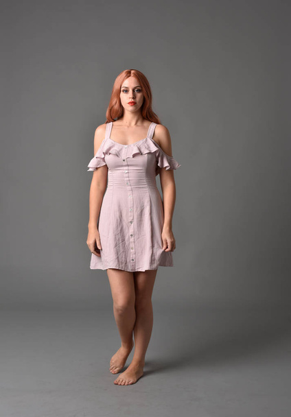 retrato de longitud completa de la niña con vestido de verano de color rosa. pose de pie sobre fondo gris estudio
 - Foto, imagen