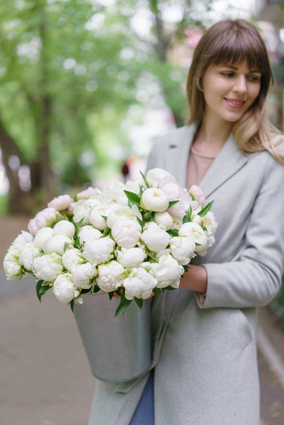 selective focus on flowers. Beautiful bouquet of white peonies in woomans hands . Floral composition, daylight. Wallpaper. Vertical photo - 写真・画像