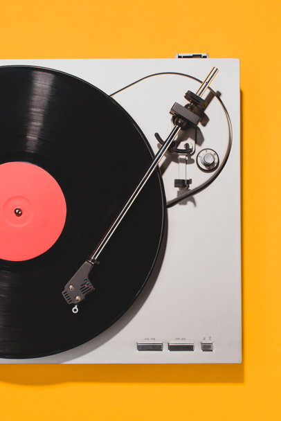 bovenaanzicht van retro vinyl speler en record geïsoleerd op geel - Foto, afbeelding