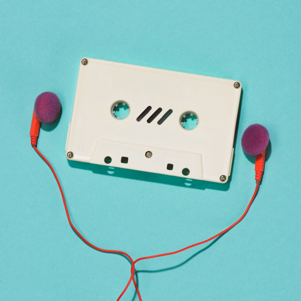 flat lay with white retro audio cassette and earphones isolated on blue - Φωτογραφία, εικόνα