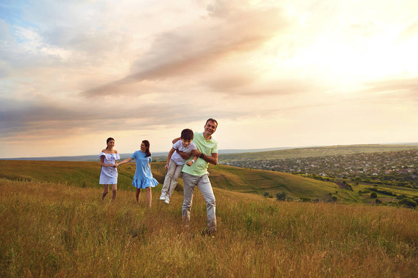 A family is having fun walking in the sunset - Фото, зображення