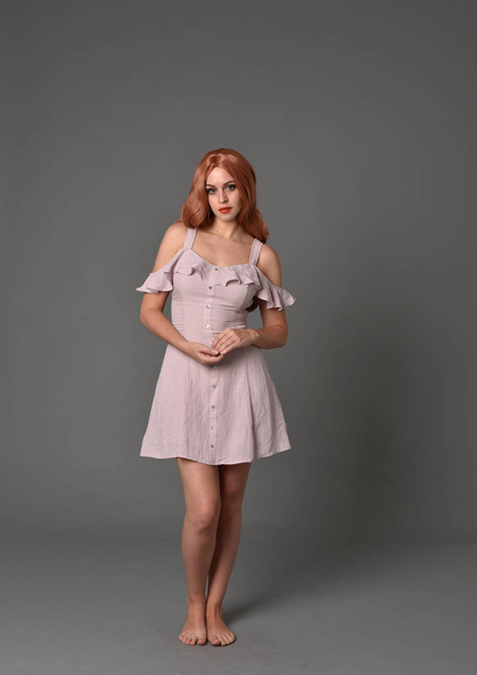 retrato de longitud completa de la niña con vestido de verano de color rosa. pose de pie sobre fondo gris estudio
 - Foto, imagen