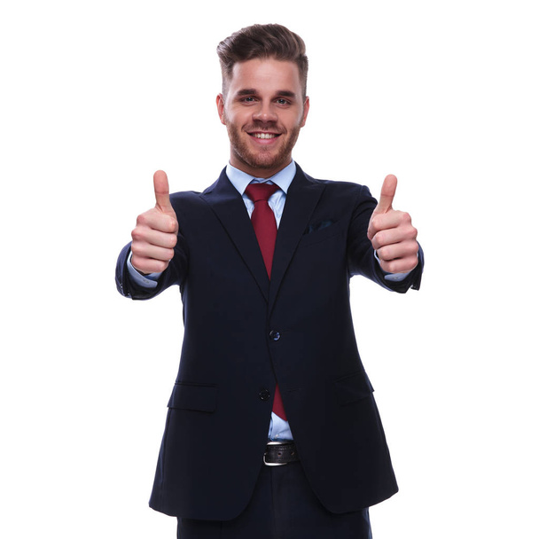 retrato de hombre de negocios sonriente en traje azul marino haciendo pulgares hacia arriba signo mientras está de pie sobre fondo blanco
 - Foto, imagen
