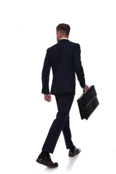 espalda de hombre de negocios en traje azul marino caminando un mirando a un lado sobre fondo blanco
 - Foto, imagen