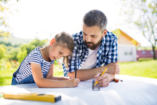 Father with a small daughter outside, planning wooden birdhouse. - 写真・画像