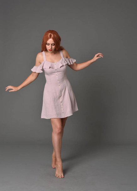 tam uzunlukta pembe yazlık elbise giyen kız portresi. gri studio arka plan üzerinde ayakta poz - Fotoğraf, Görsel