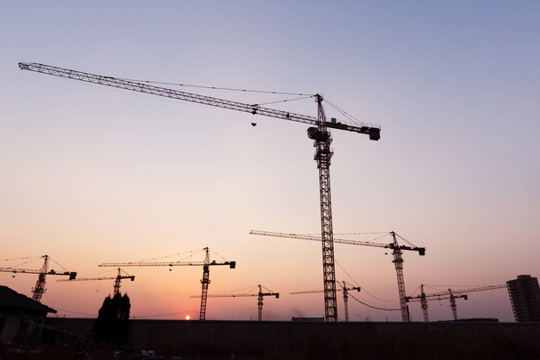 промышленные краны с закатом на строительной площадке
 - Фото, изображение