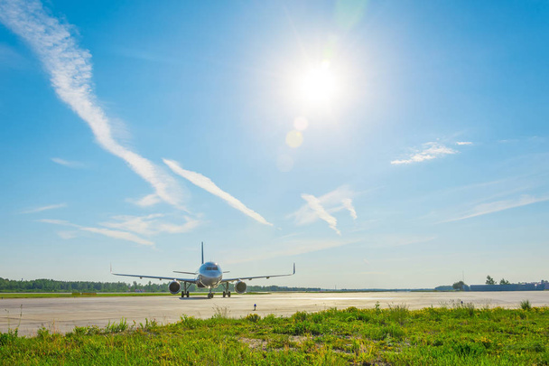 Vliegtuig op de stuurinrichting track op de luchthaven, tegen de achtergrond van een schilderachtige hemel in de wolken zon - Foto, afbeelding