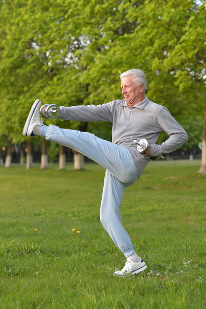 Elderly man exercising with dumbbells - Photo, Image