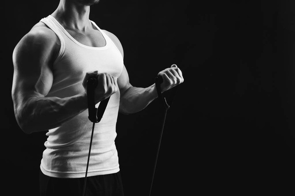 Lekkoatletycznego mięśni mężczyzna wykonujących w sposób elastyczny expander w black  - Zdjęcie, obraz