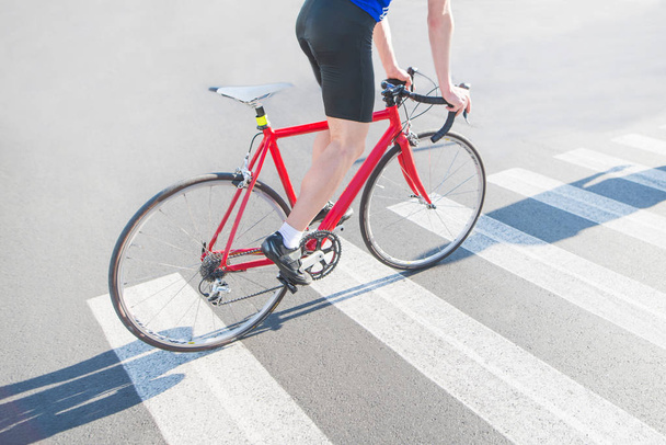 Велосипедист їде на зебру на червоному міському велосипеді. Їздити містом на велосипеді. Спортивна концепція
. - Фото, зображення