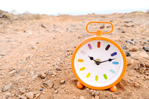 Orologio analogico classico nella sabbia sul deserto roccioso - Foto, immagini