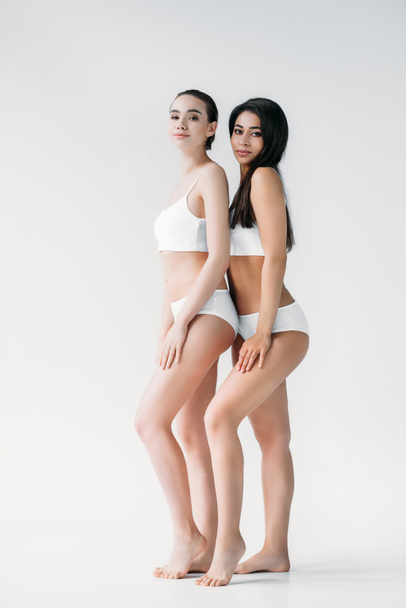 attractive multicultural women posing in white lingerie isolated on gray background  - Фото, зображення