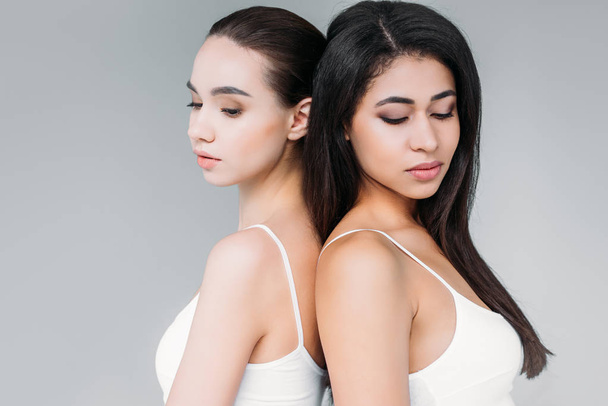 attractive multicultural women standing back to back isolated on gray background  - Photo, Image