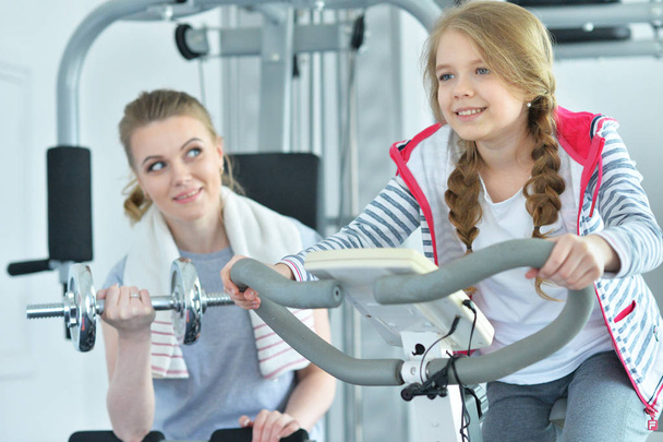 Sportliche junge Frau trainiert mit Teenager-Tochter im Fitnessstudio - Foto, Bild