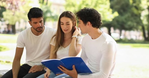 Three students studying together sitting on a bench outdoor - Foto, Imagem