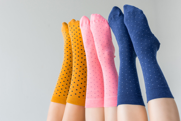 περικομμένη εικόνα γυναικεία πόδια σε διαφορετικές πολύχρωμες κάλτσες απομονώνονται σε γκρίζο φόντο  - Φωτογραφία, εικόνα