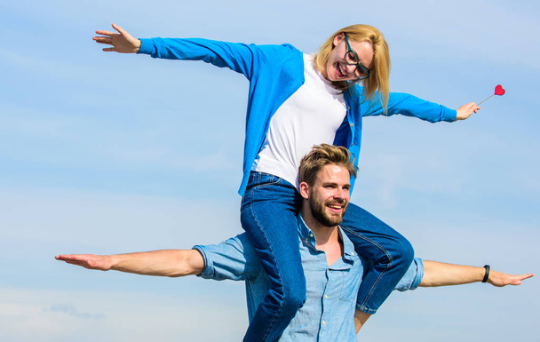 Couple in love enjoy feeling freedom outdoor sunny day. Couple happy date having fun together. Man carries girlfriend on shoulders, sky background. Lovers enjoy date and feeling free. Freedom concept - Photo, Image