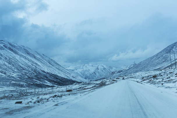 empty road through snow mountains - Foto, imagen