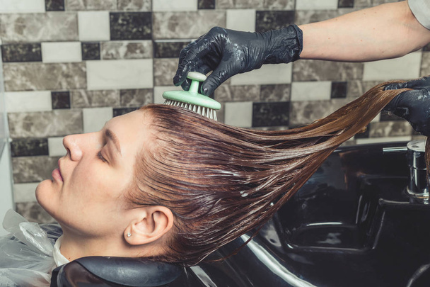 Pielęgnacja włosów procedury w gabinecie kosmetycznym. Salon fryzjerski szczotkuje włosy kobiety rozprzestrzeniania maska leczenia lub odżywka - Zdjęcie, obraz