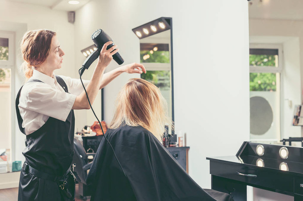 esteticista golpe secado cabello de mujer en salón de belleza
 - Foto, Imagen