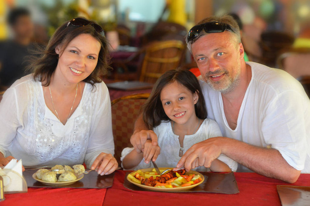 hymyilevä perhe syö kahvilassa
 - Valokuva, kuva