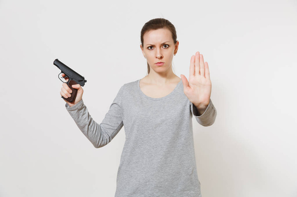 Woman with gun in hand showing stop gesture with palm isolated on white background. Girl hand no shooting symbol. Stop violence, weapons in school control, no killing people children, problem concept - 写真・画像
