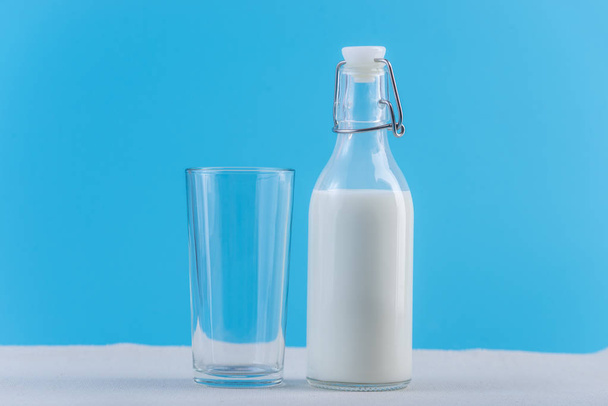 Taze süt ve mavi arka plan cam cam şişe. Renkli minimalizm. Kalsiyum sağlıklı süt ürünleri kavramı - Fotoğraf, Görsel