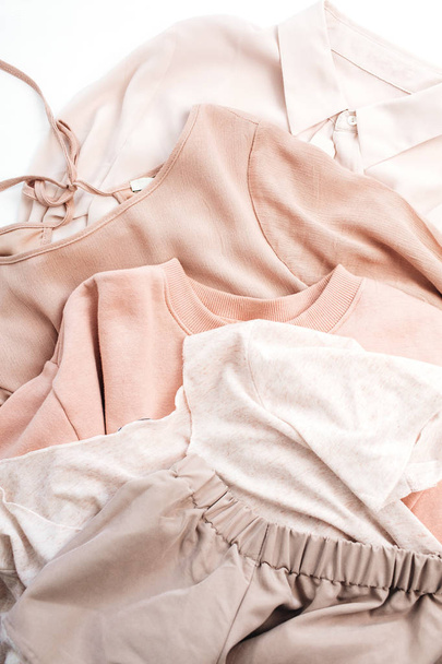 Γυναικείο απαλό παστέλ ροζ ρούχα. Πουλόβερ, φούστα, πουκάμισο σε άσπρο φόντο. Έννοια της μόδας ελάχιστη επίπεδη lay, κορυφαία προβολή. - Φωτογραφία, εικόνα