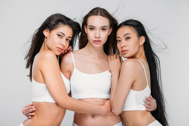 beautiful multicultural women posing in white bra, isolated on grey - Foto, immagini