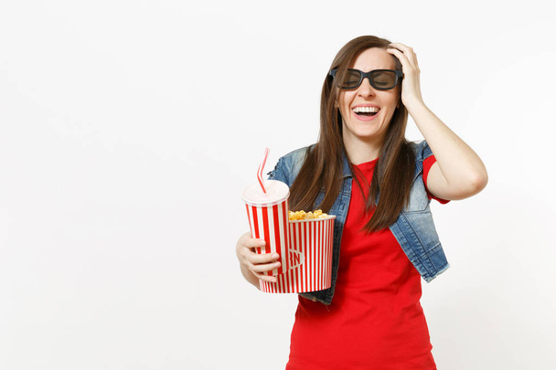 Jovem mulher rindo em óculos 3d assistindo filme, segurando balde de pipoca e xícara de plástico de refrigerante ou cola, mantendo a mão perto da cabeça isolada no fundo branco. Emoções no conceito de cinema
 - Foto, Imagem