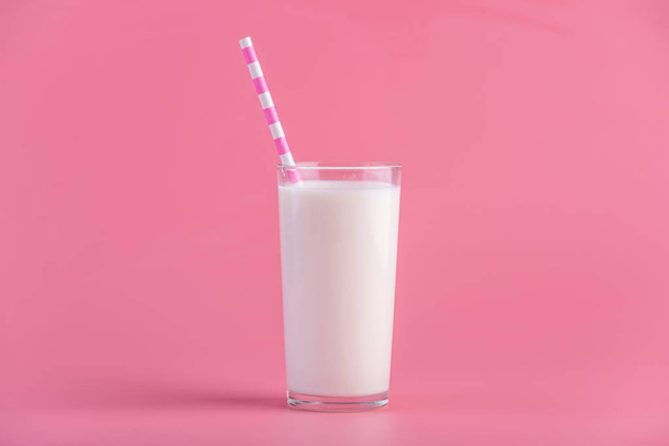 Стакан свежего молока с соломинкой на розовом фоне. Красочный минимализм. Концепция здоровых молочных продуктов с кальцием
 - Фото, изображение
