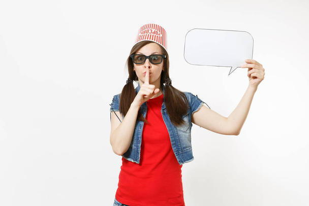 Mujer conmocionada en gafas 3D con cubo para palomitas de maíz en la cabeza sosteniendo dicen nube con lugar para el texto, copyspace, mostrando gesto shhh con el dedo en los labios aislados sobre fondo blanco. Emociones en el cine
 - Foto, imagen