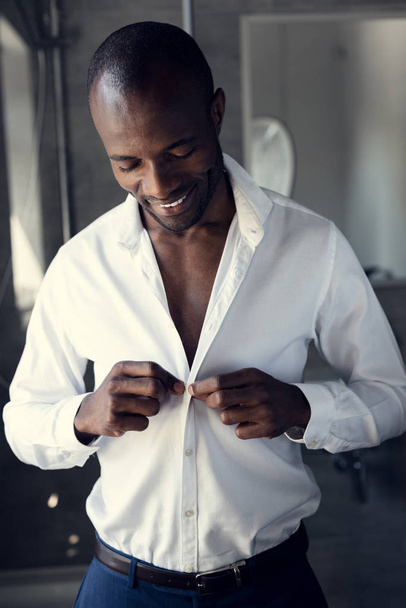 happy young businessman buttoning his white shirt before work - Фото, зображення