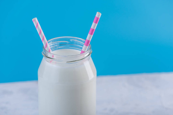 Garrafa de vidro de leite fresco com duas palhinhas em fundo azul. minimalismo colorido. O conceito de produtos lácteos saudáveis com cálcio
 - Foto, Imagem