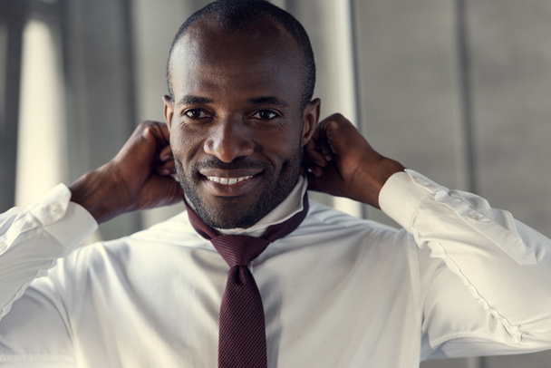 happy young businessman in white shirt putting on his tie - Fotó, kép