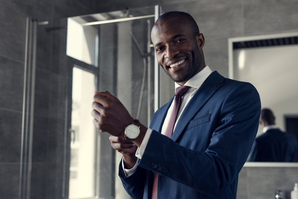 щасливий молодий бізнесмен одягає наручний годинник у ванну кімнату
 - Фото, зображення