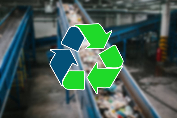 Señal de reciclaje de residuos. La planta de clasificación y procesamiento de residuos es borrosa en el fondo
 - Foto, imagen