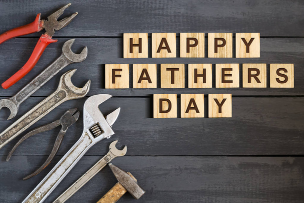Happy Father's Day inscription on wooden cubes with working tools on a wooden background. Greetings and gifts.Holidays. - Valokuva, kuva