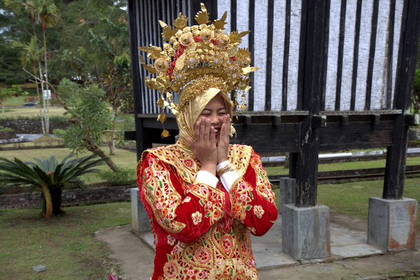 Mulher no vestido de casamento tradicional de West Sumatra está sorrindo timidamente
 - Foto, Imagem