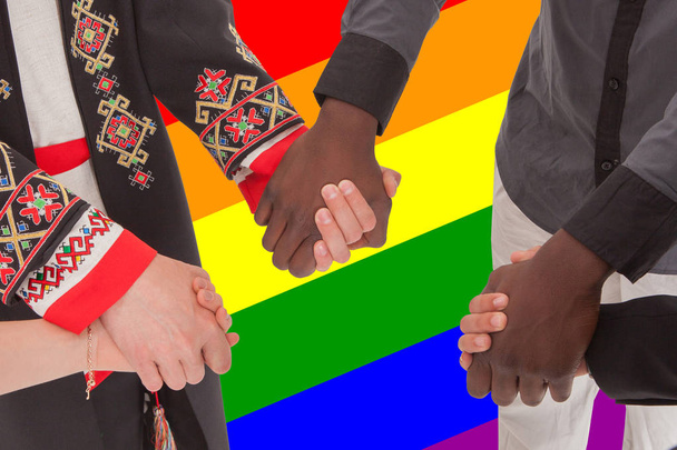 People of different nationalities hold hands against the background of the LGBT flag - Photo, Image